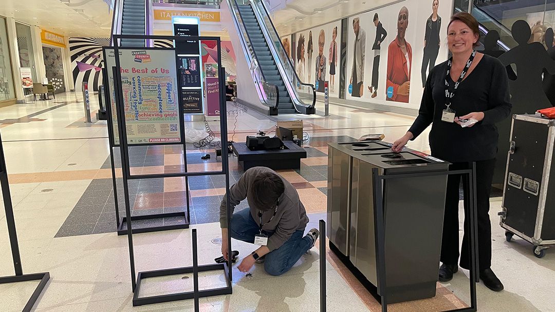 A man and a woman are working on a table in a mall.