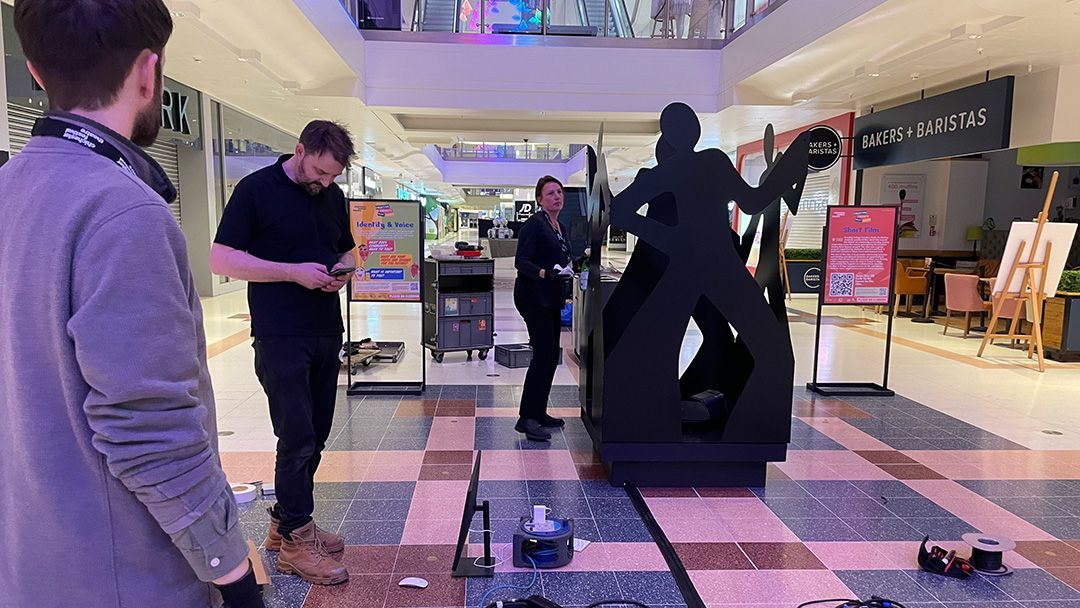 A group of people are standing around a statue in a mall.