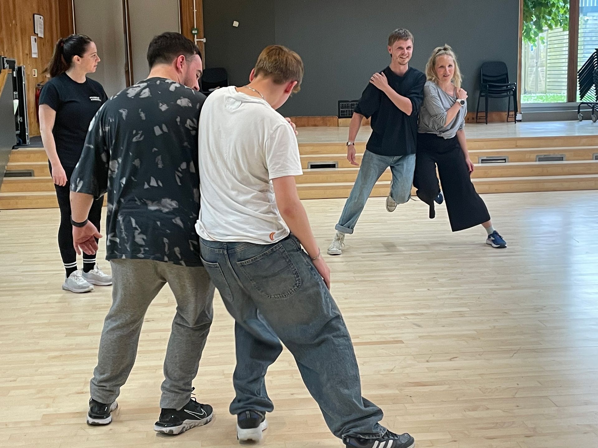 A group of people are dancing on a wooden floor