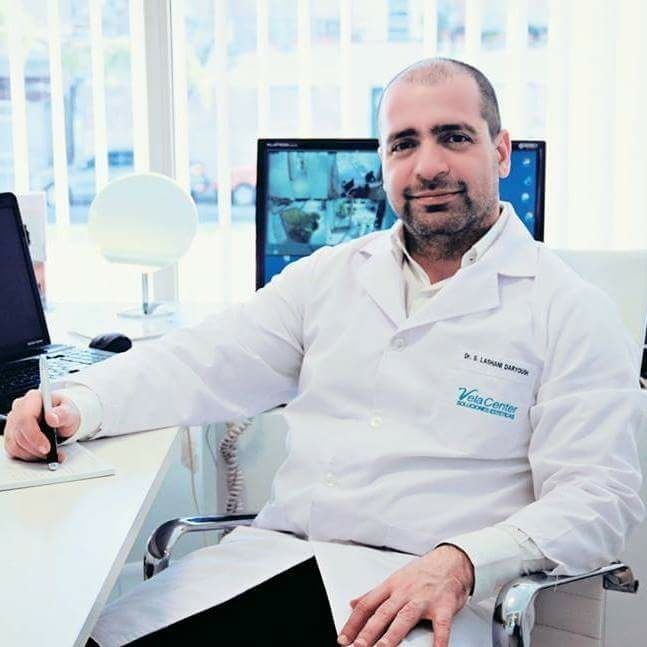 Un hombre con una bata blanca de laboratorio está sentado en un escritorio.