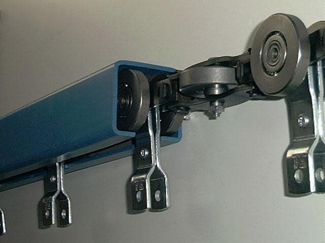 A blue railing with wheels attached to it is hanging on a wall.