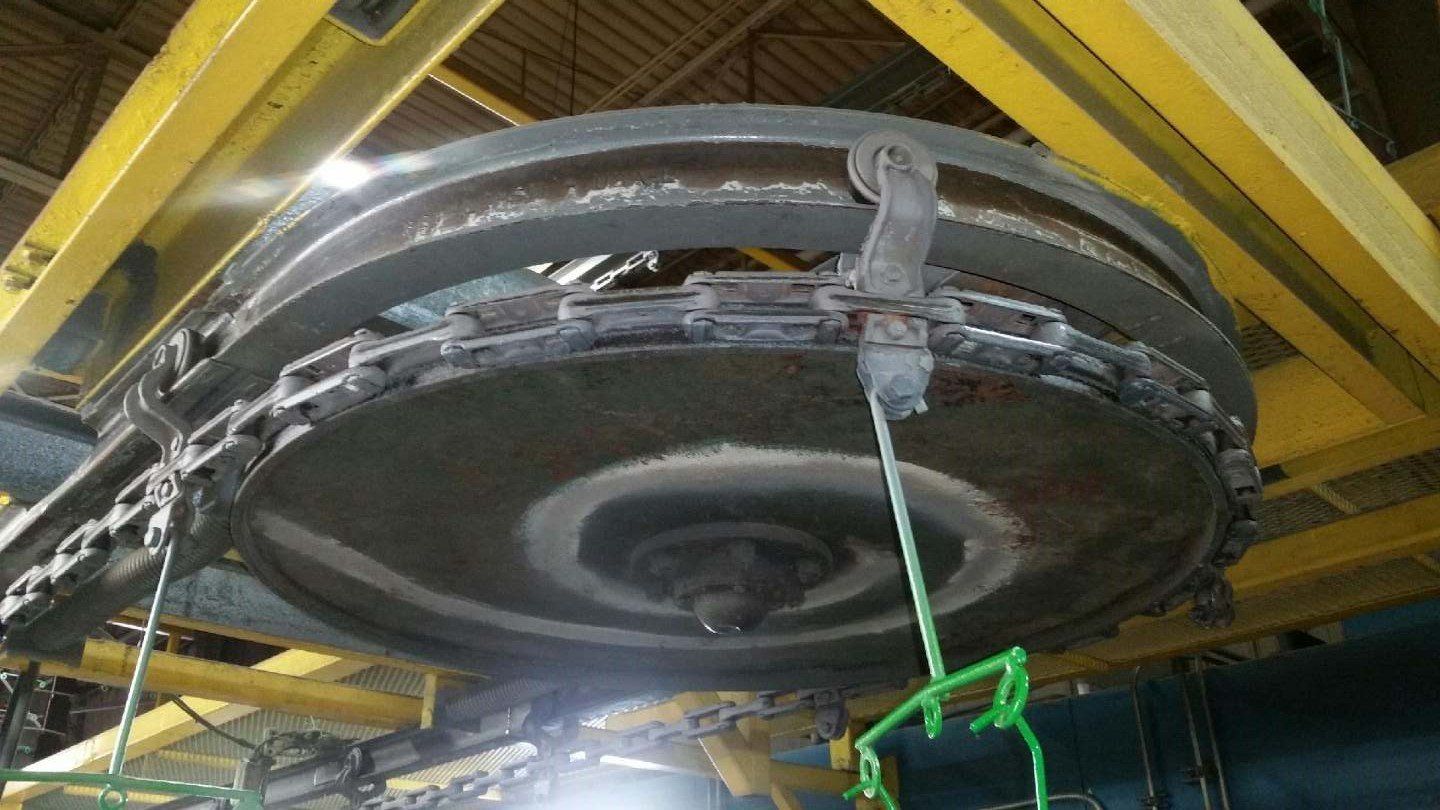 A large metal object is hanging from a crane in a factory.