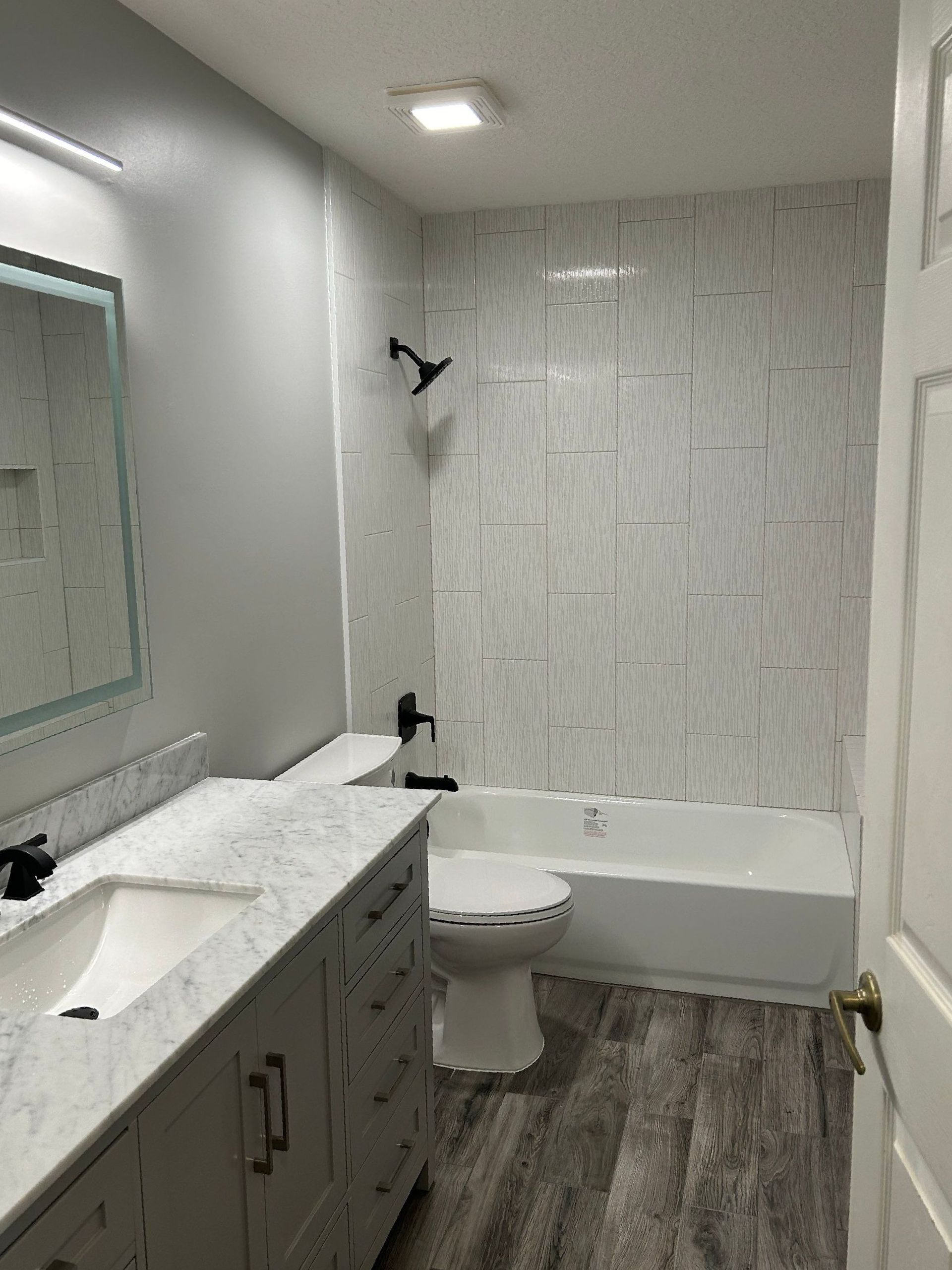 A bathroom with a toilet , sink , bathtub and mirror.