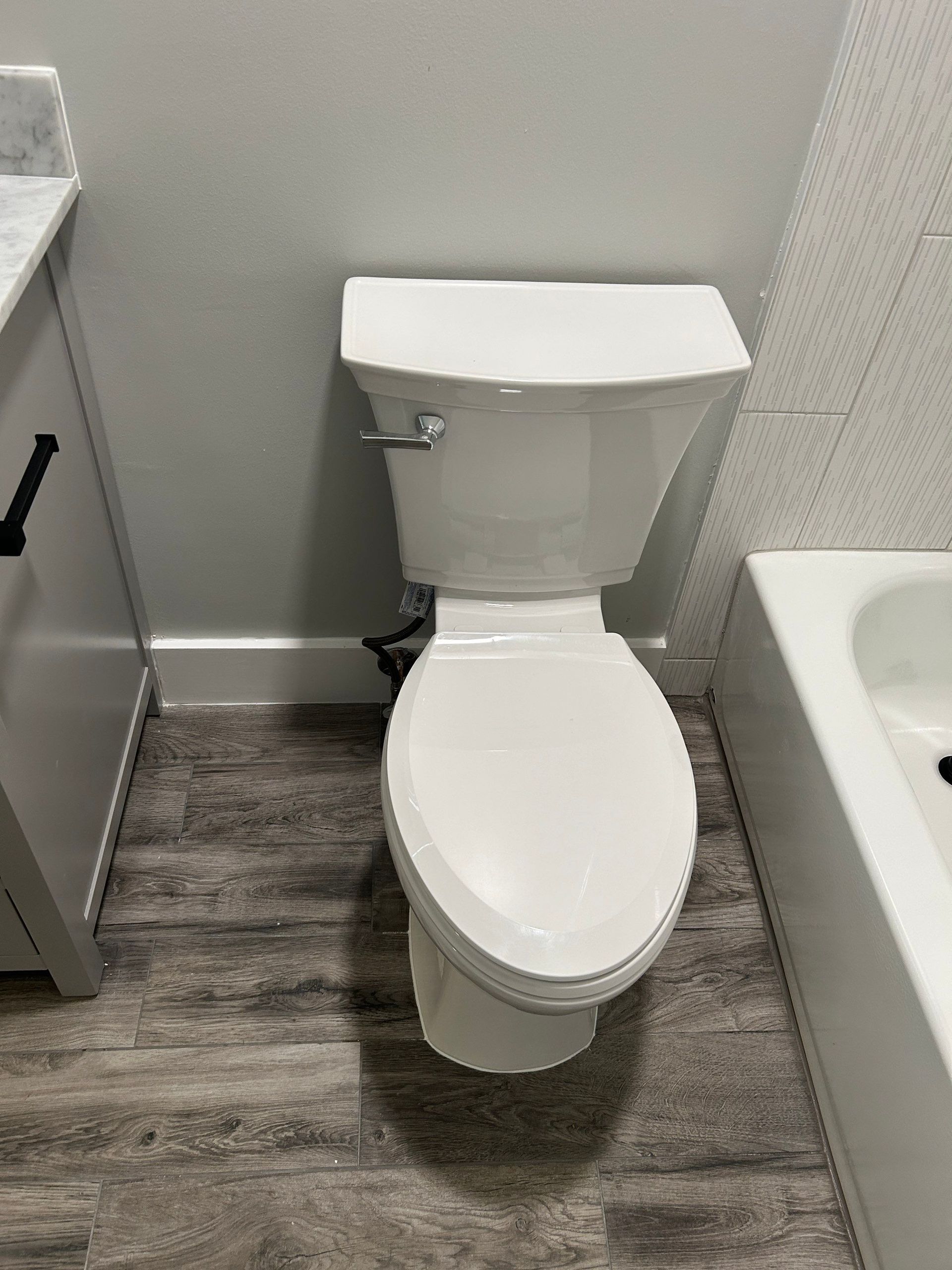 A white toilet is sitting in a bathroom next to a bathtub.
