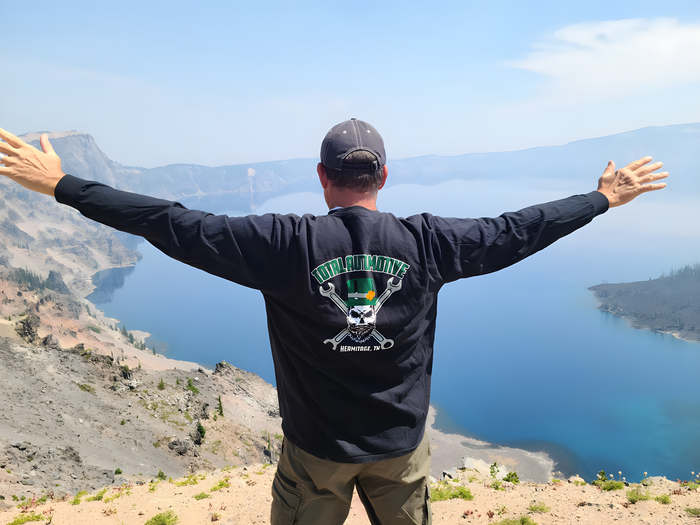 Man with arms outstretched, overlooking Crater Lake | Total Automotive