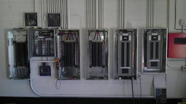 A row of electrical panels are lined up on a wall.