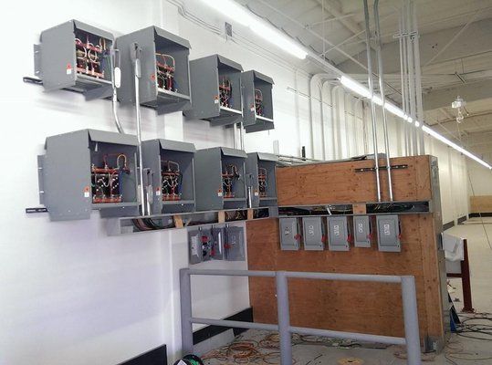 A bunch of electrical boxes are hanging on the wall in a room.