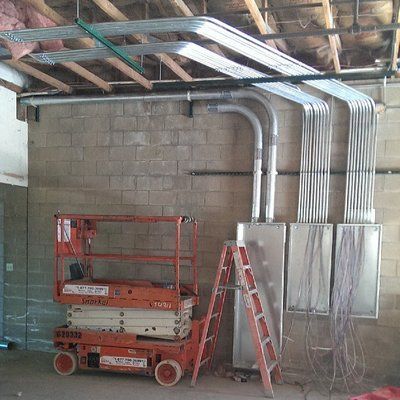 A ladder is sitting next to a scissor lift in a room.