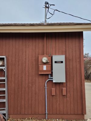 A red building with a ladder and a meter on it.