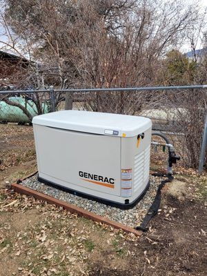 A generator is sitting in the dirt next to a fence.