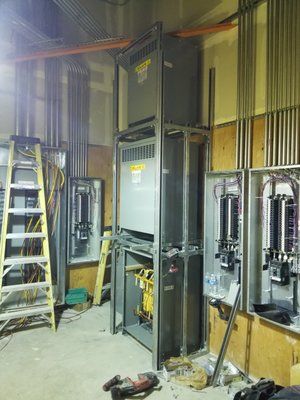 A room with a lot of electrical equipment and a ladder.