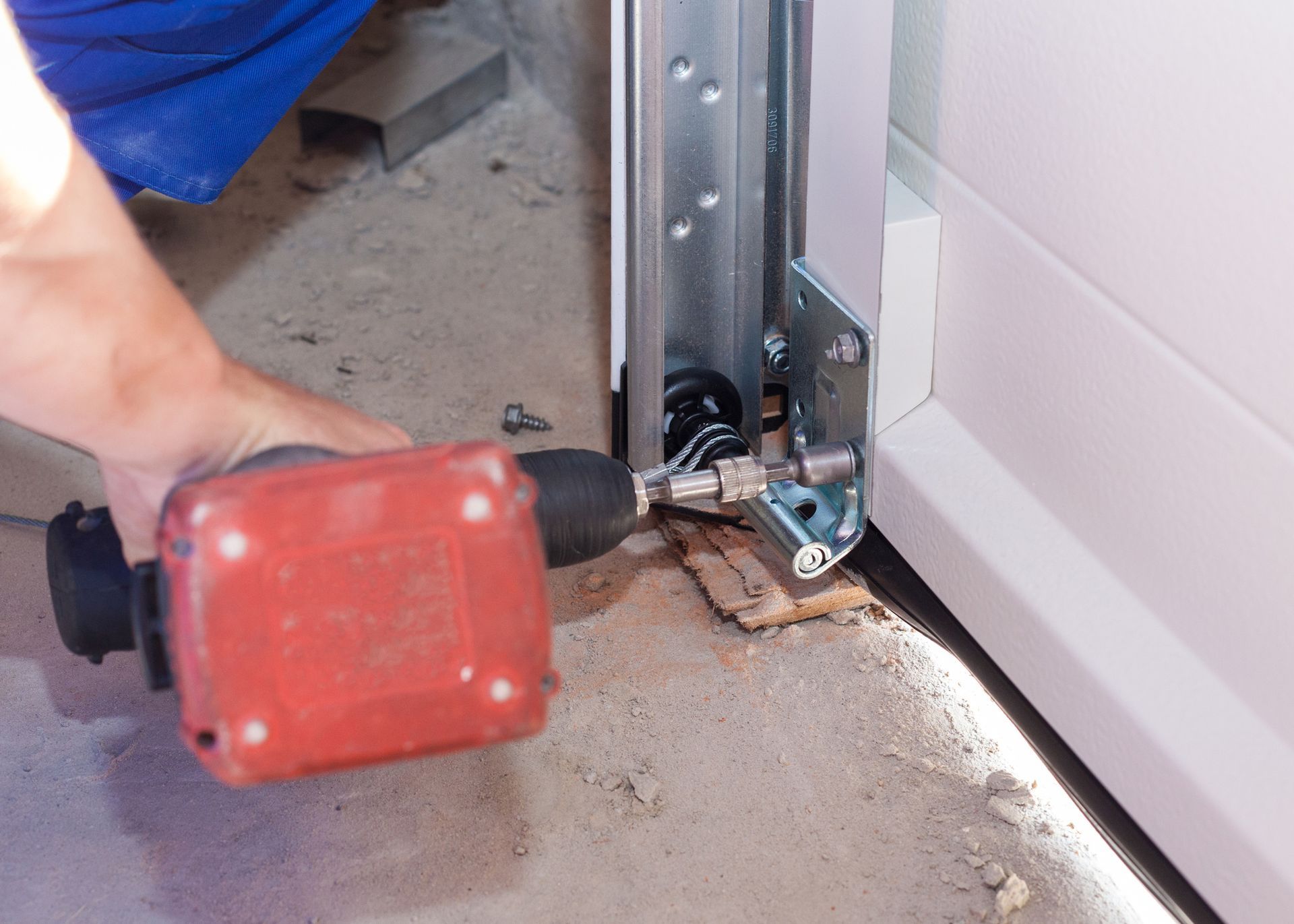 A professional worker repairing a garage door at a house.