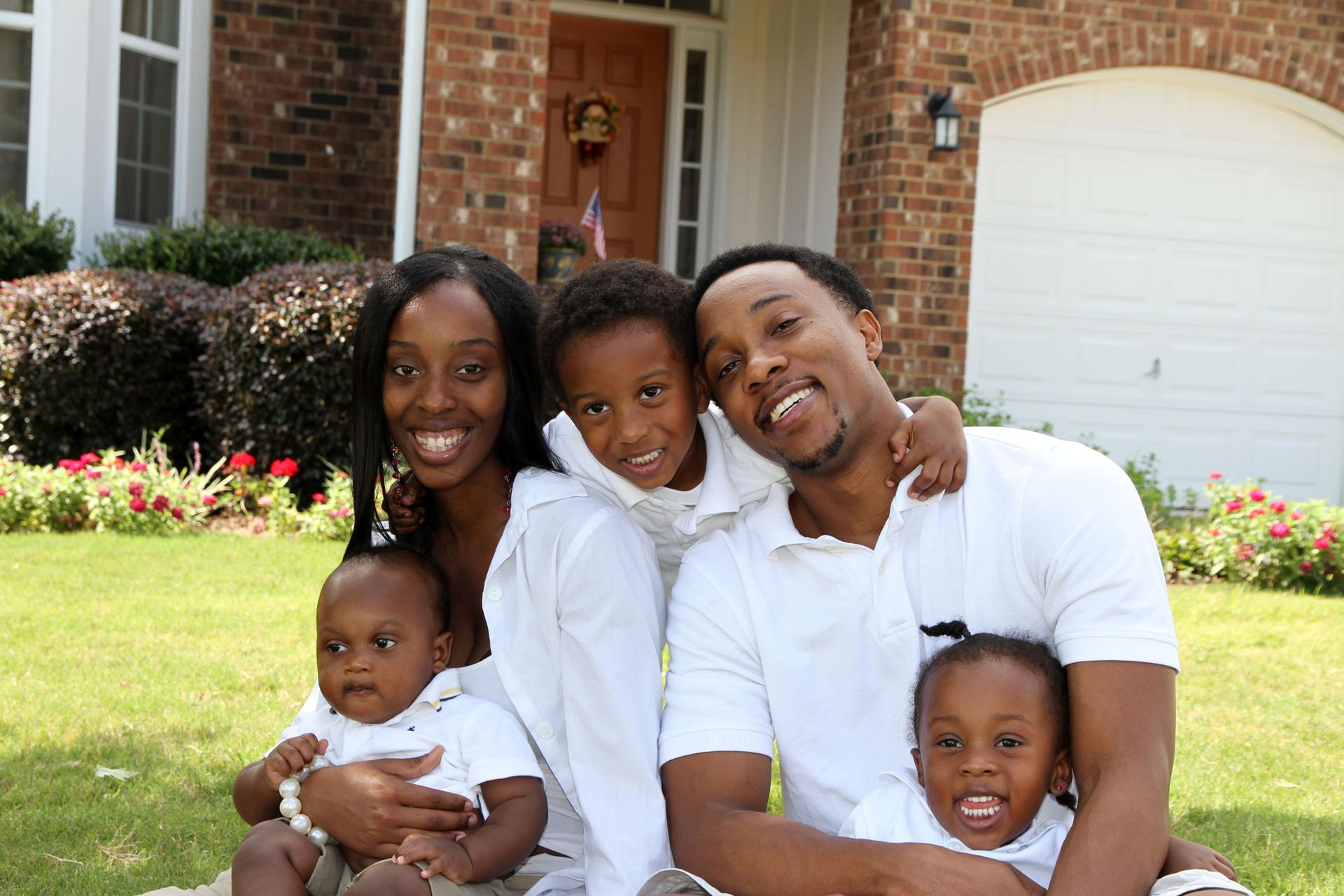 A family is posing for a picture in front of their house.