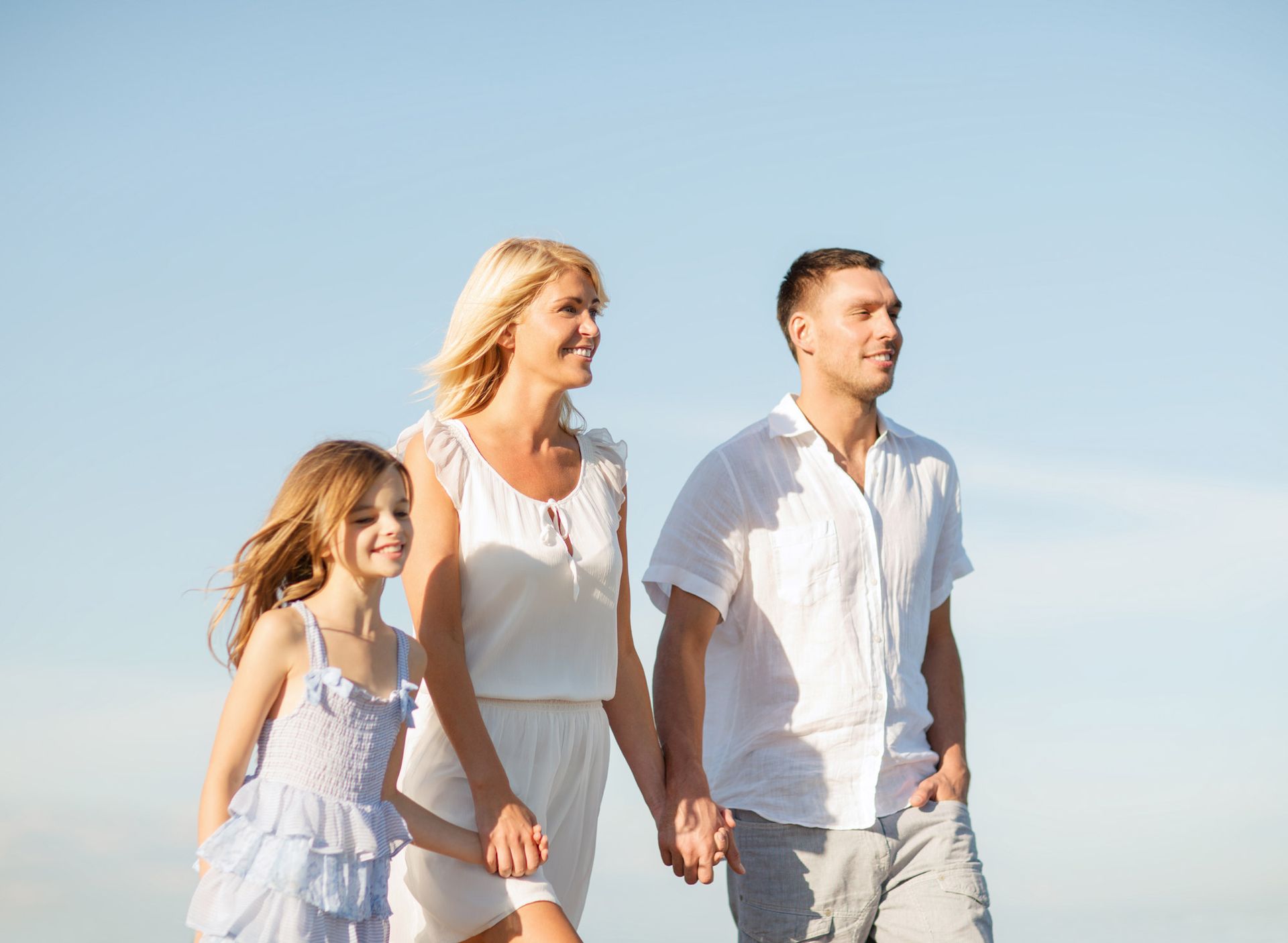 A family is holding hands while walking on the beach.