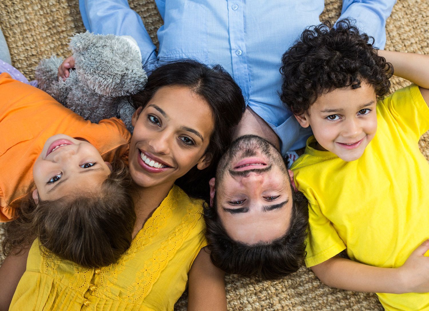 A family is laying on the floor with their heads together.