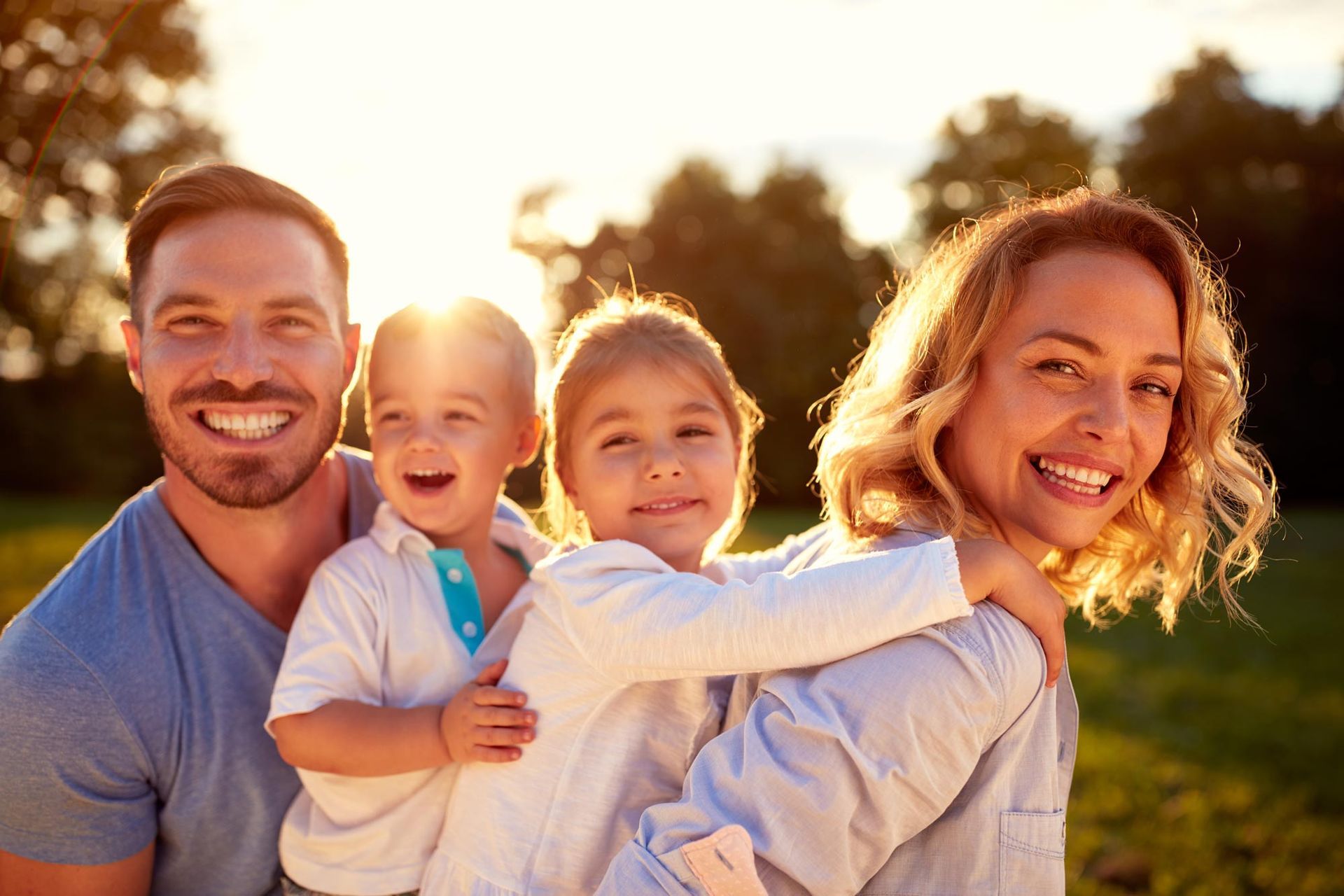 A family is posing for a picture in a park at sunset.