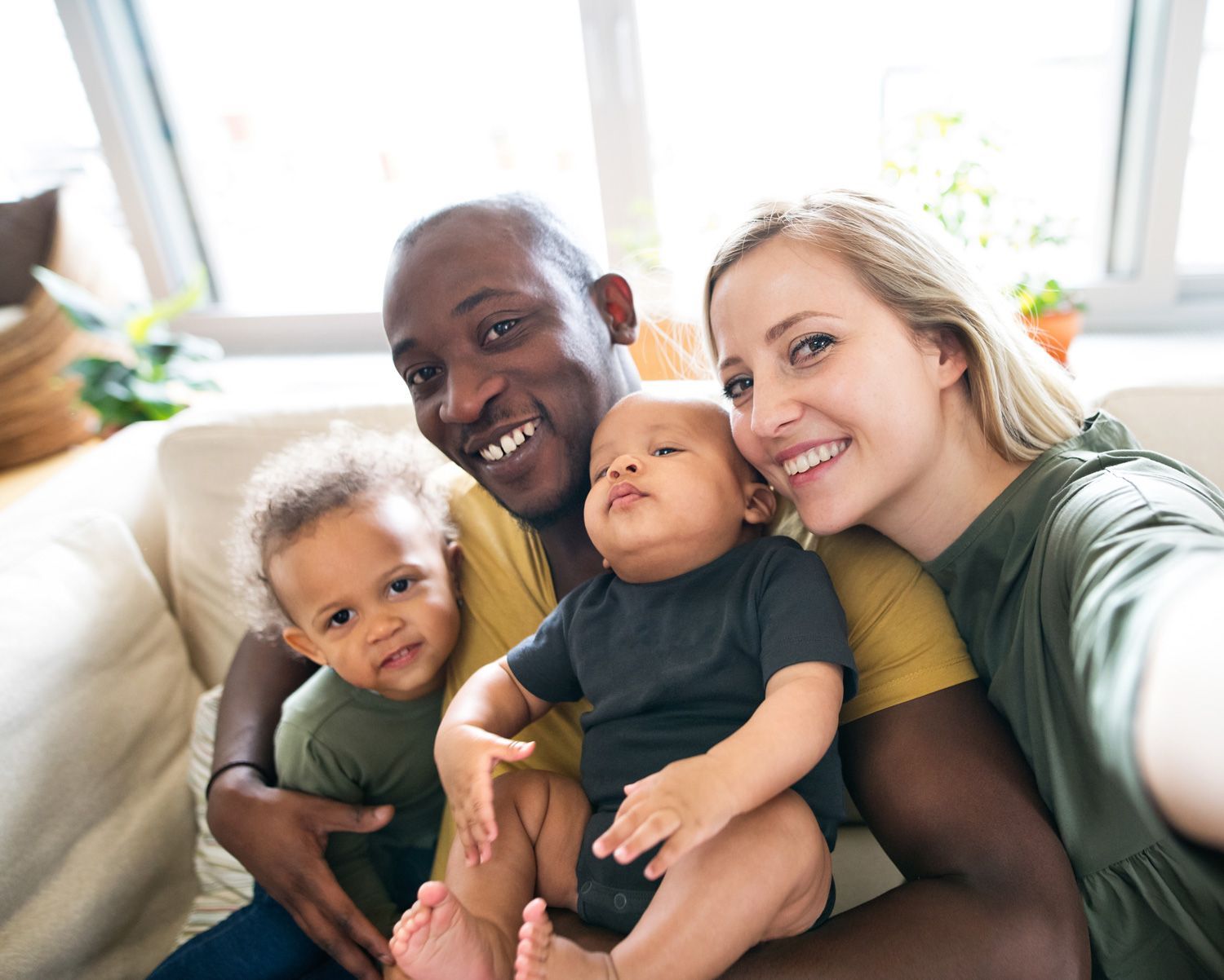 A family is sitting on a couch taking a selfie.