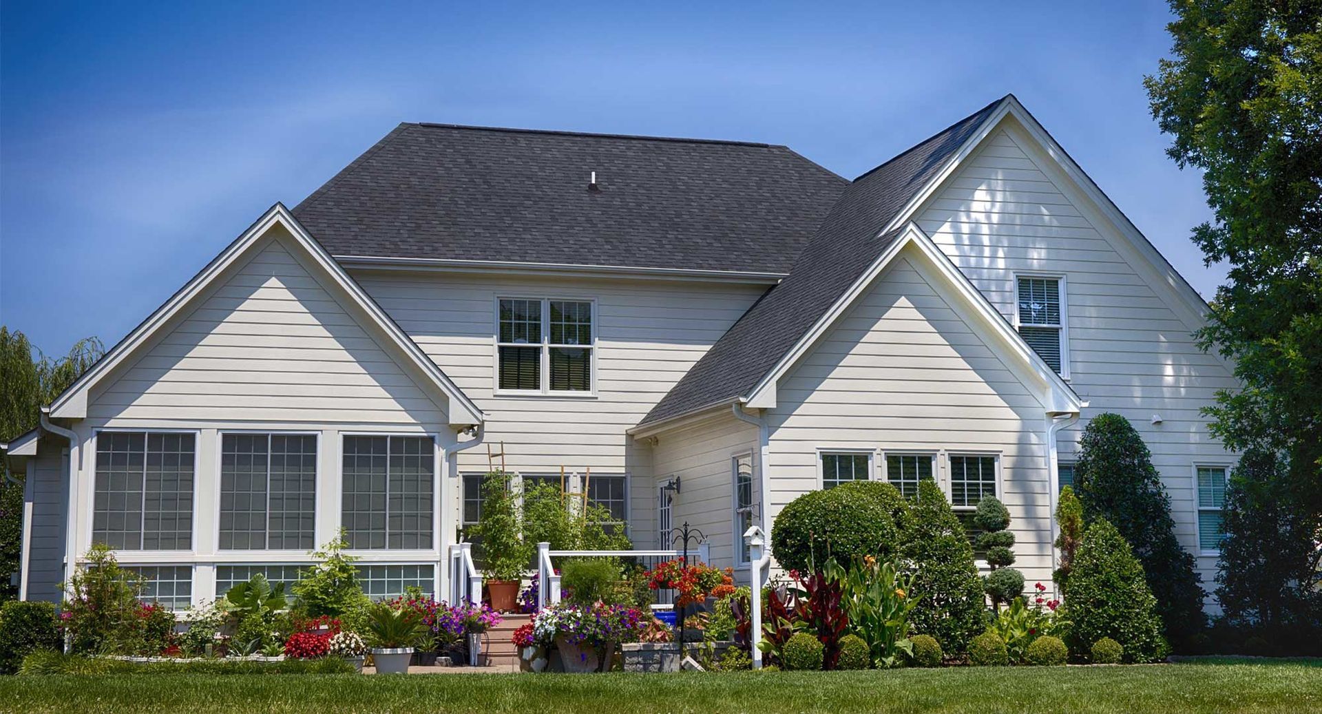 A large white house with a black roof and a screened in porch