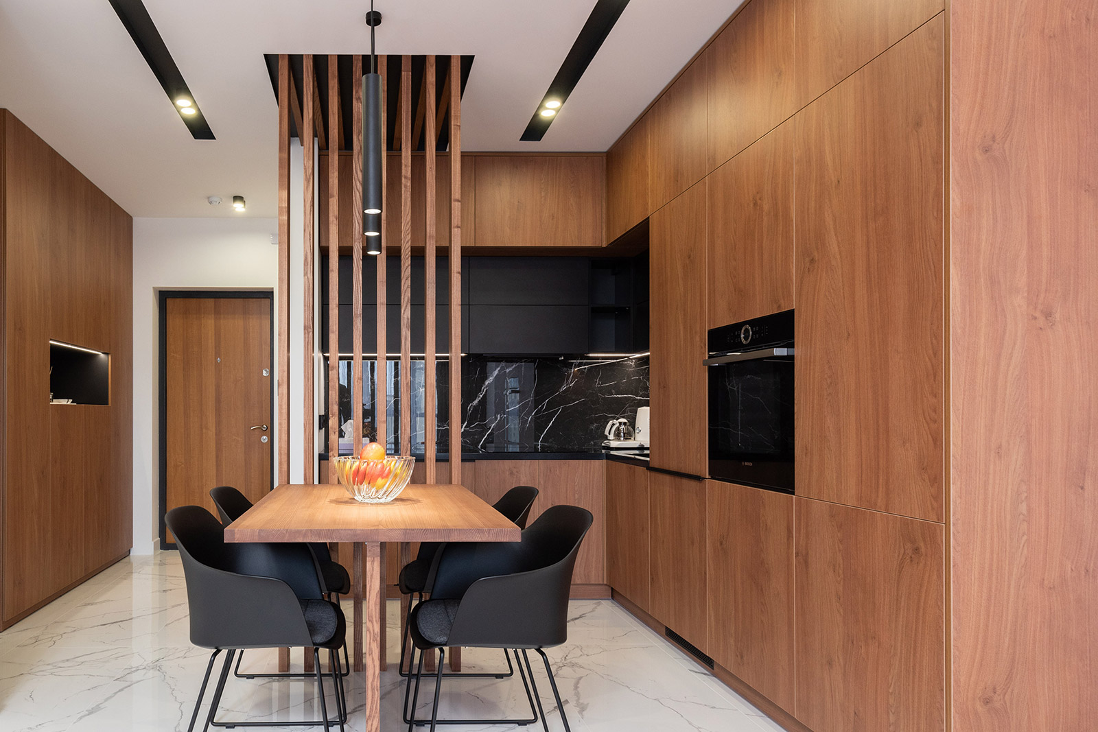 A dining room with a wooden table and chairs in a modern kitchen.