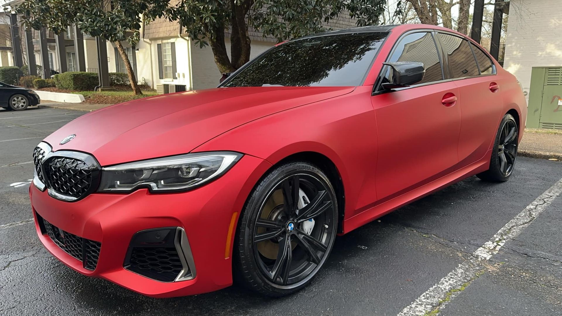 A red bmw is parked in a parking lot.