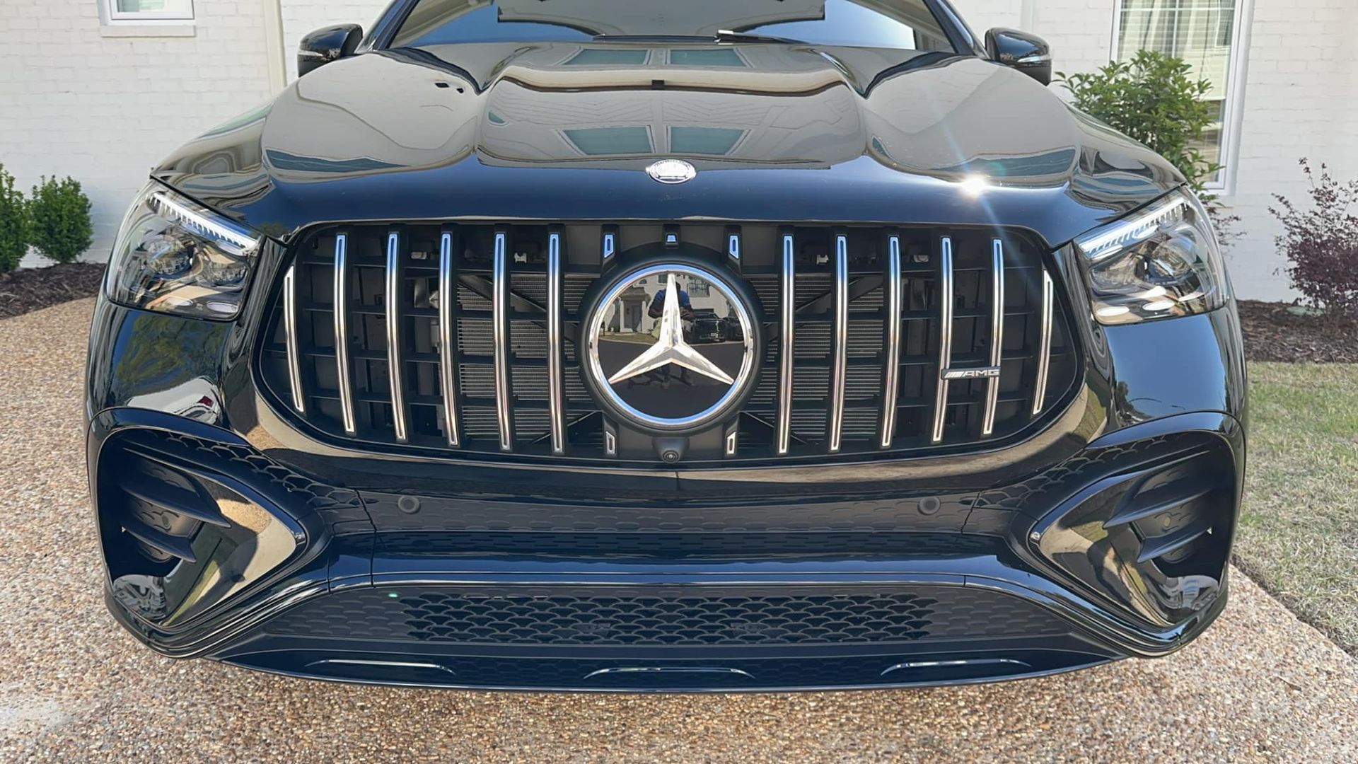 A black mercedes benz is parked in a driveway in front of a house.