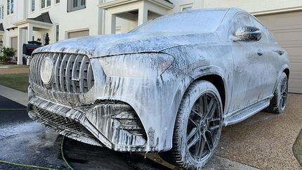 A car covered in foam is parked in front of a house.