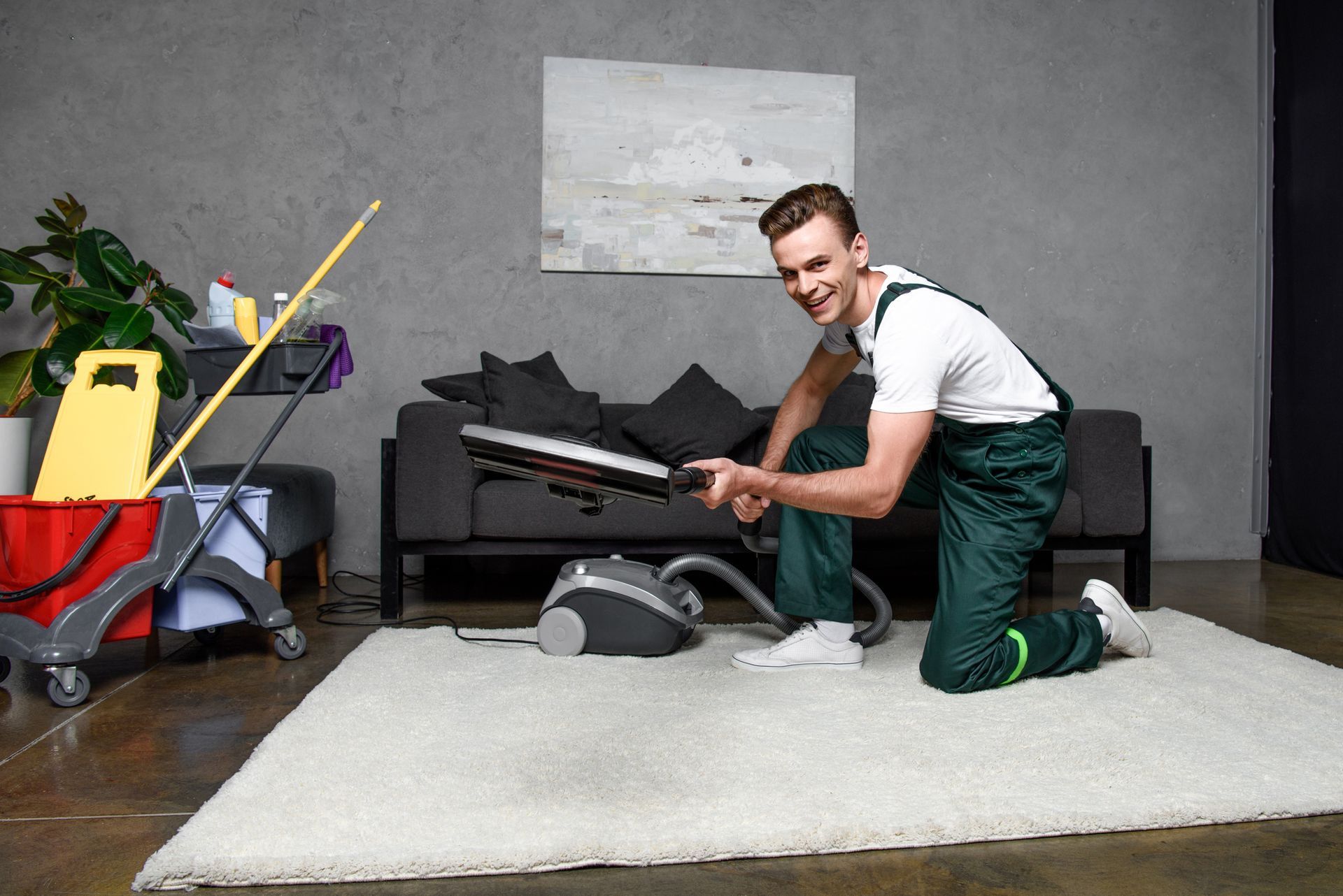 A man is cleaning a rug with a vacuum cleaner in a living room.