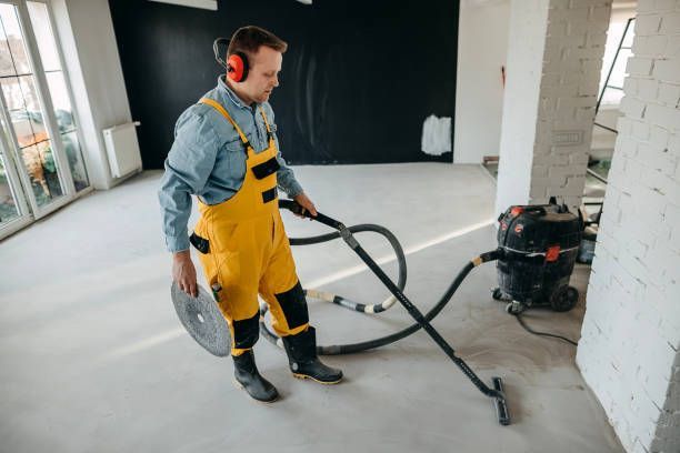 A man wearing headphones is using a vacuum cleaner in a room.