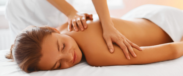 Woman receiving a shoulder massage while lying on a massage table.
