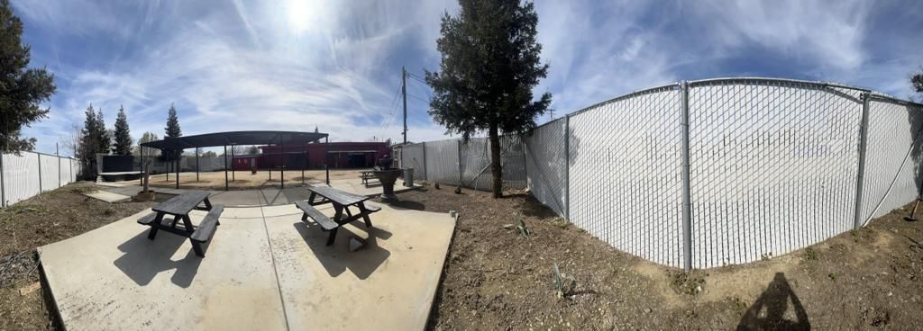 a picnic table is sitting in front of a white fence .