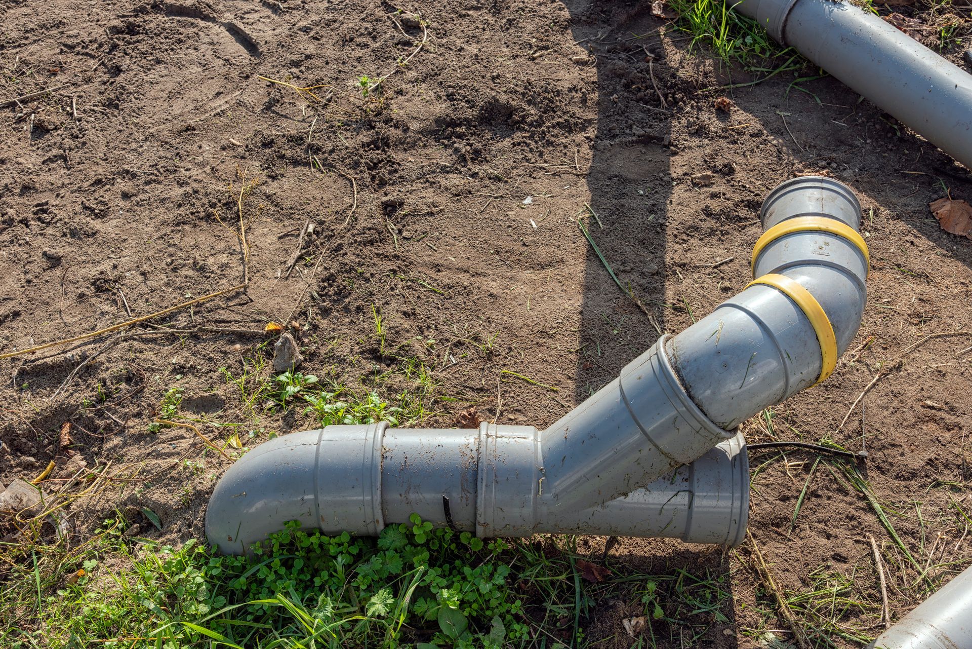 Residential Septic Repairs – PVC pipes laid on soil for home septic system installation.