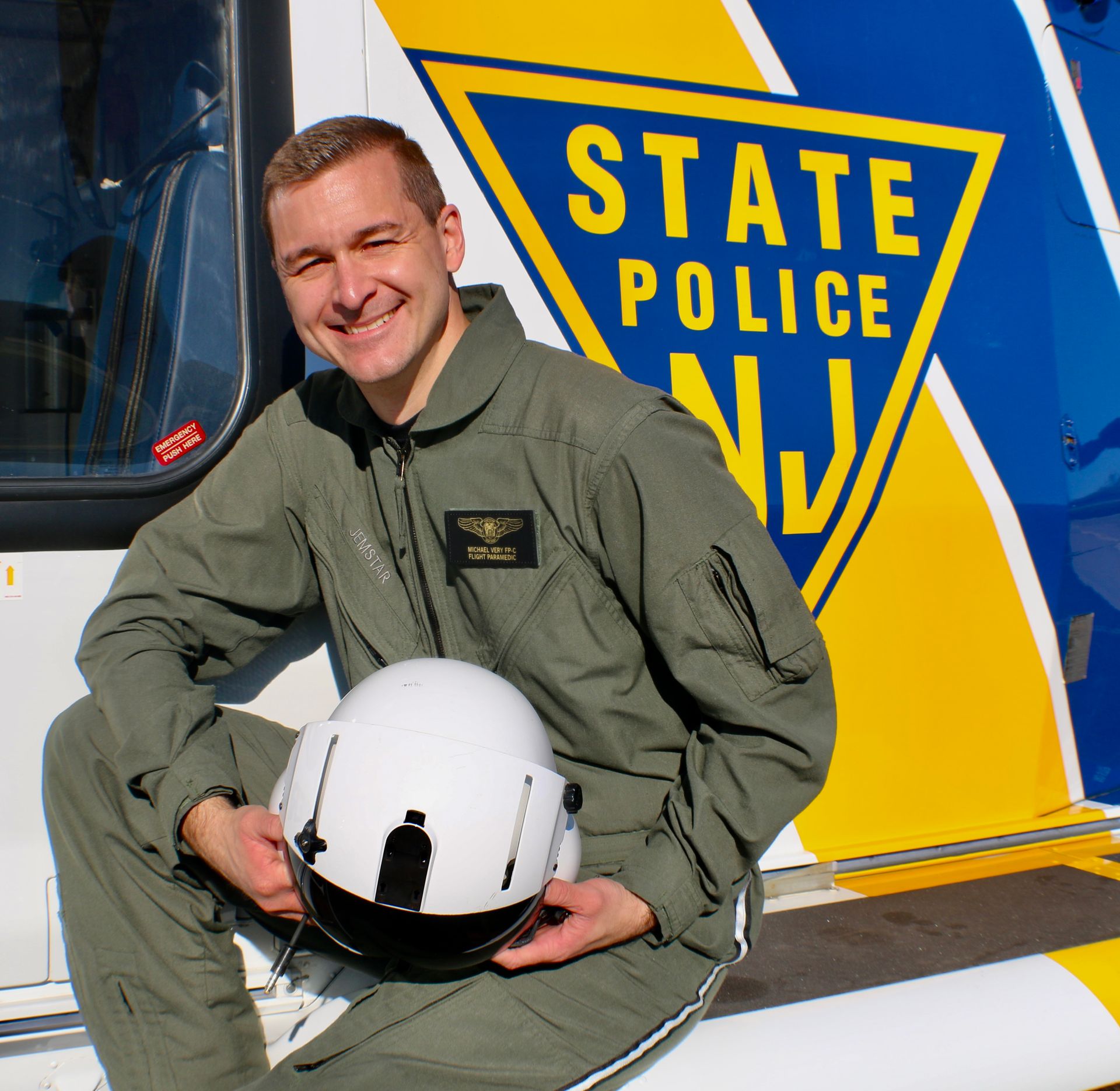 A man in a state police uniform holds a helmet