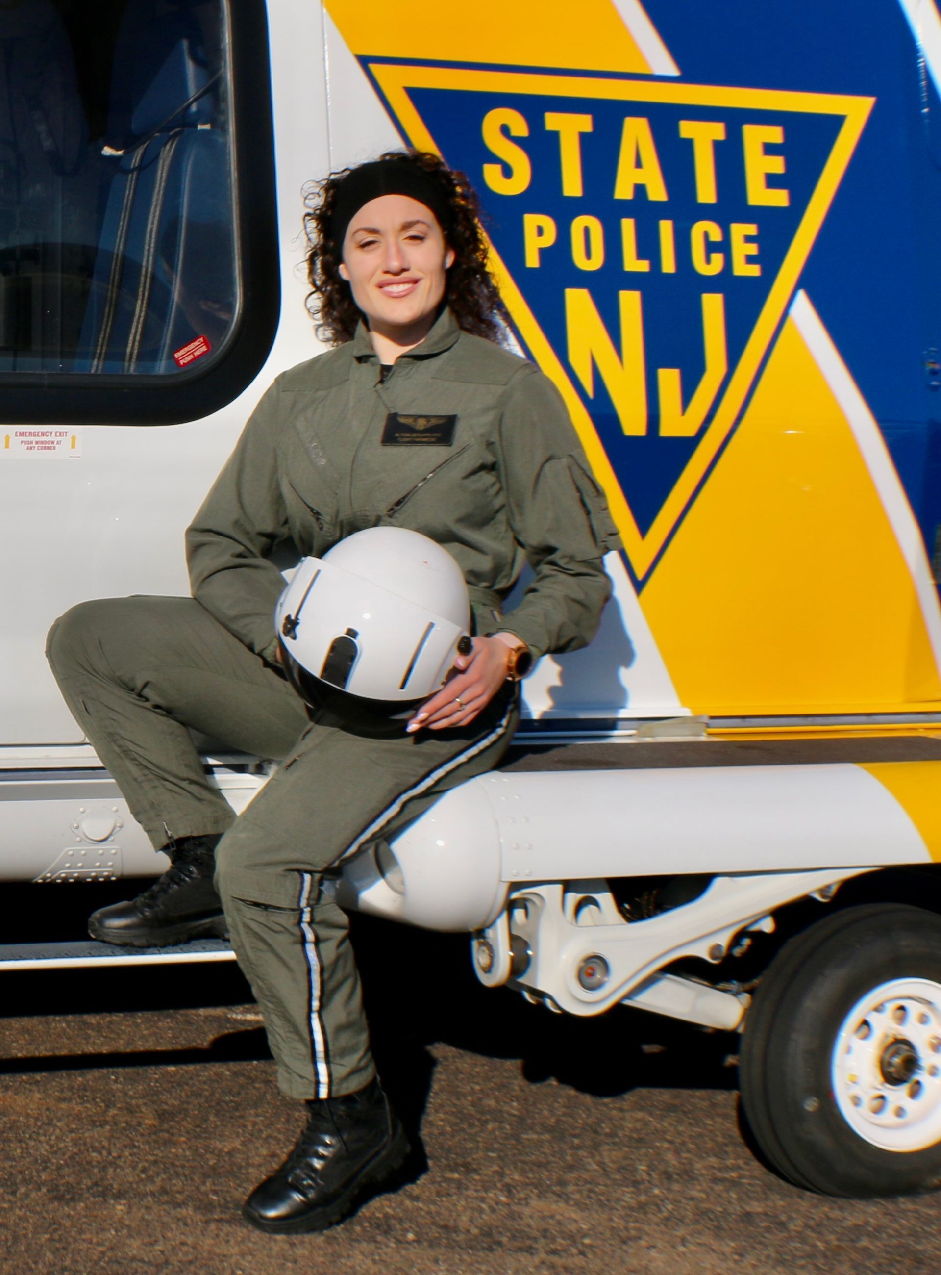 A woman is sitting on the side of a state police helicopter