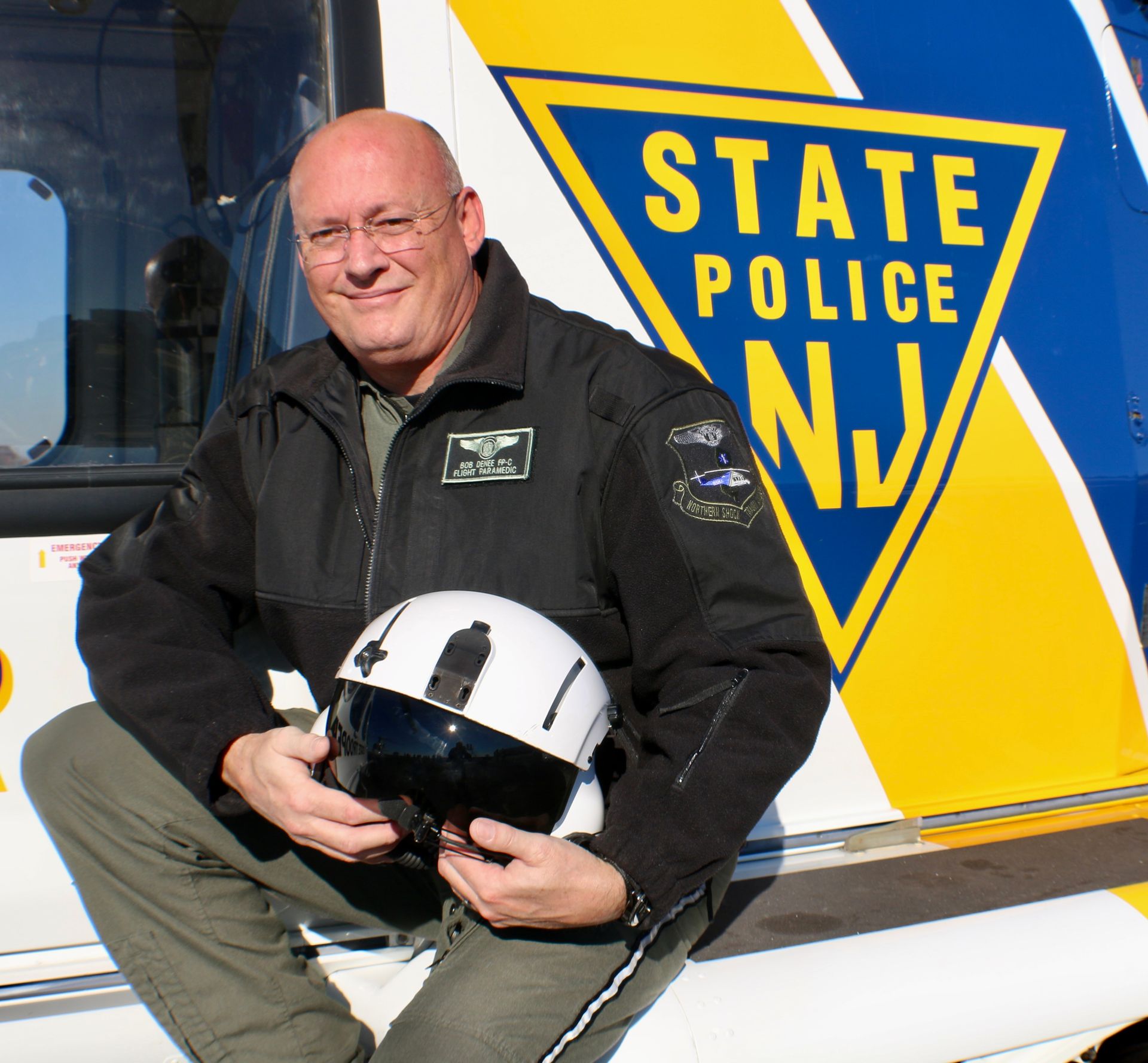 A man sits on the side of a state police vehicle