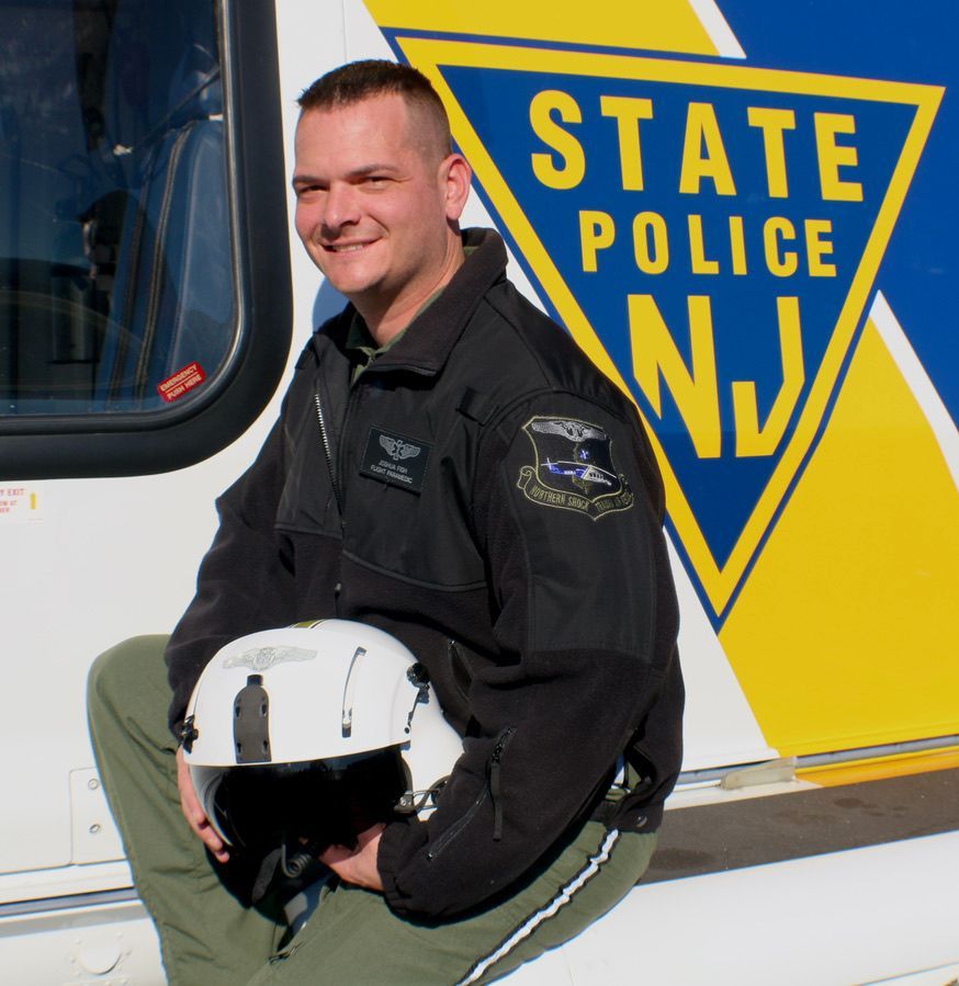 A man is sitting in front of a state police n.j. logo