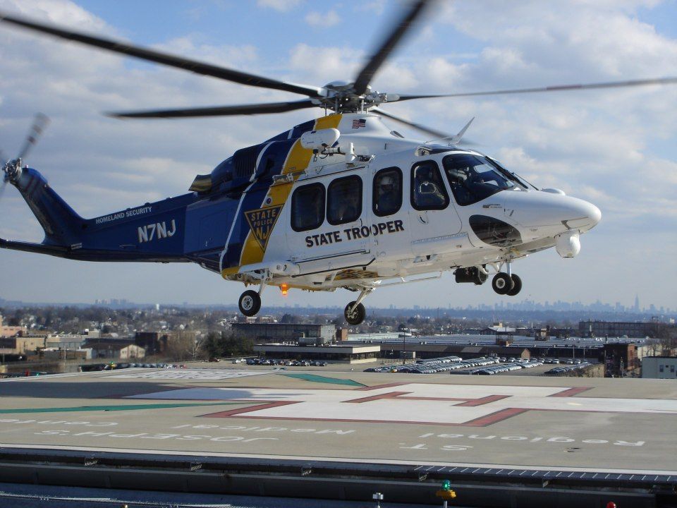A state trooper helicopter is taking off from a runway