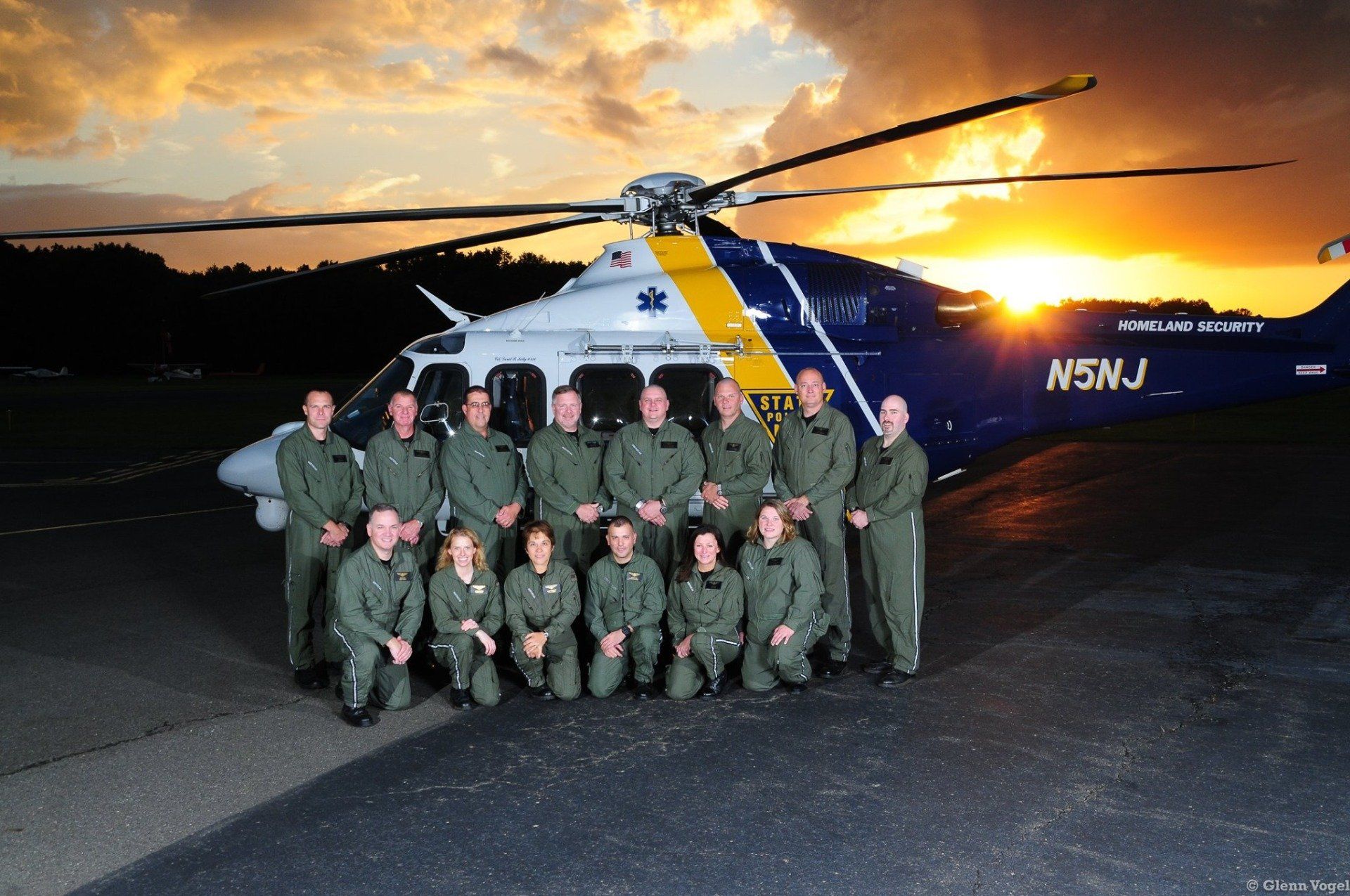 A group of people posing in front of a helicopter that says nswj