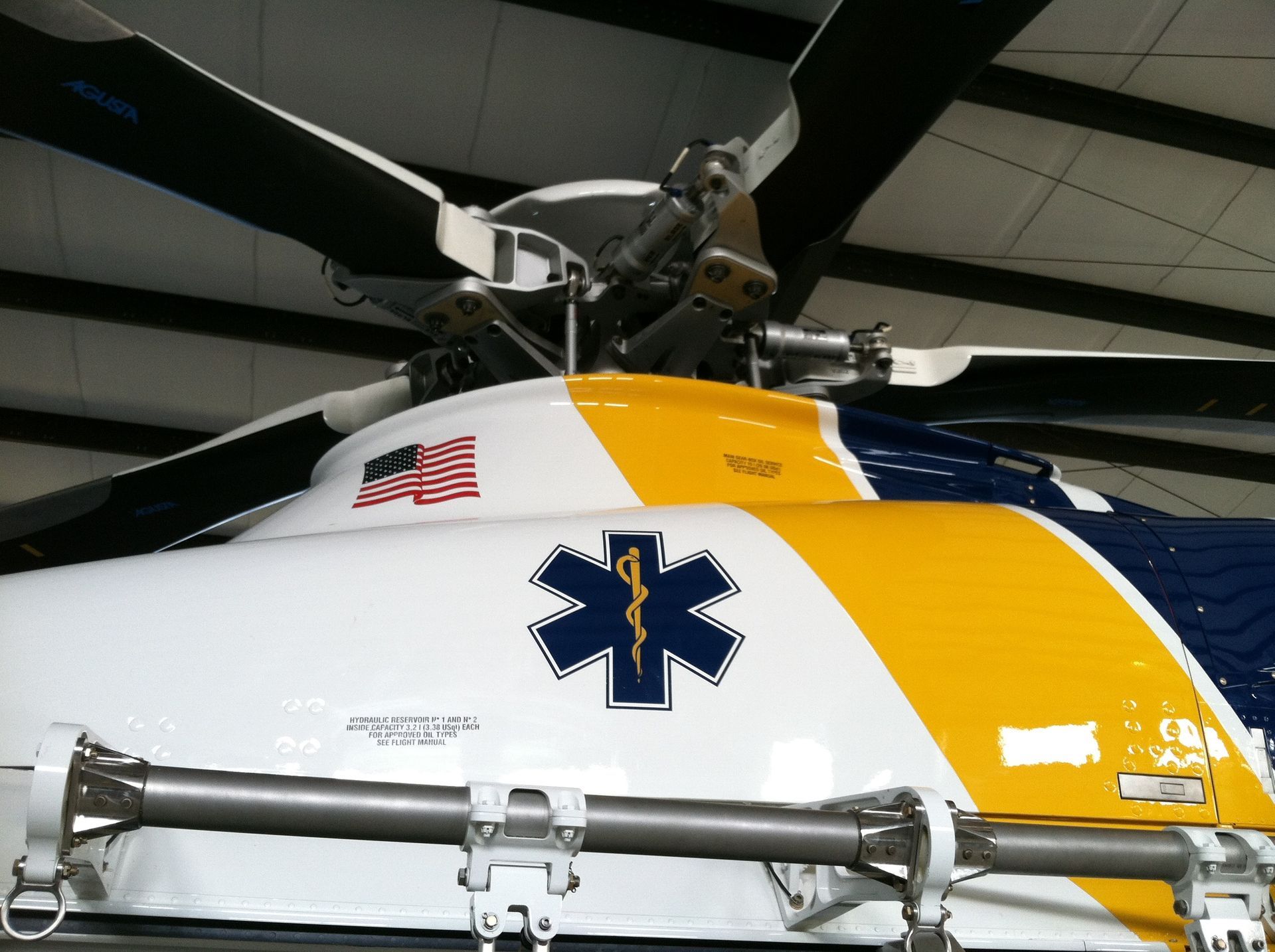A yellow and white helicopter with an ambulance symbol on the side