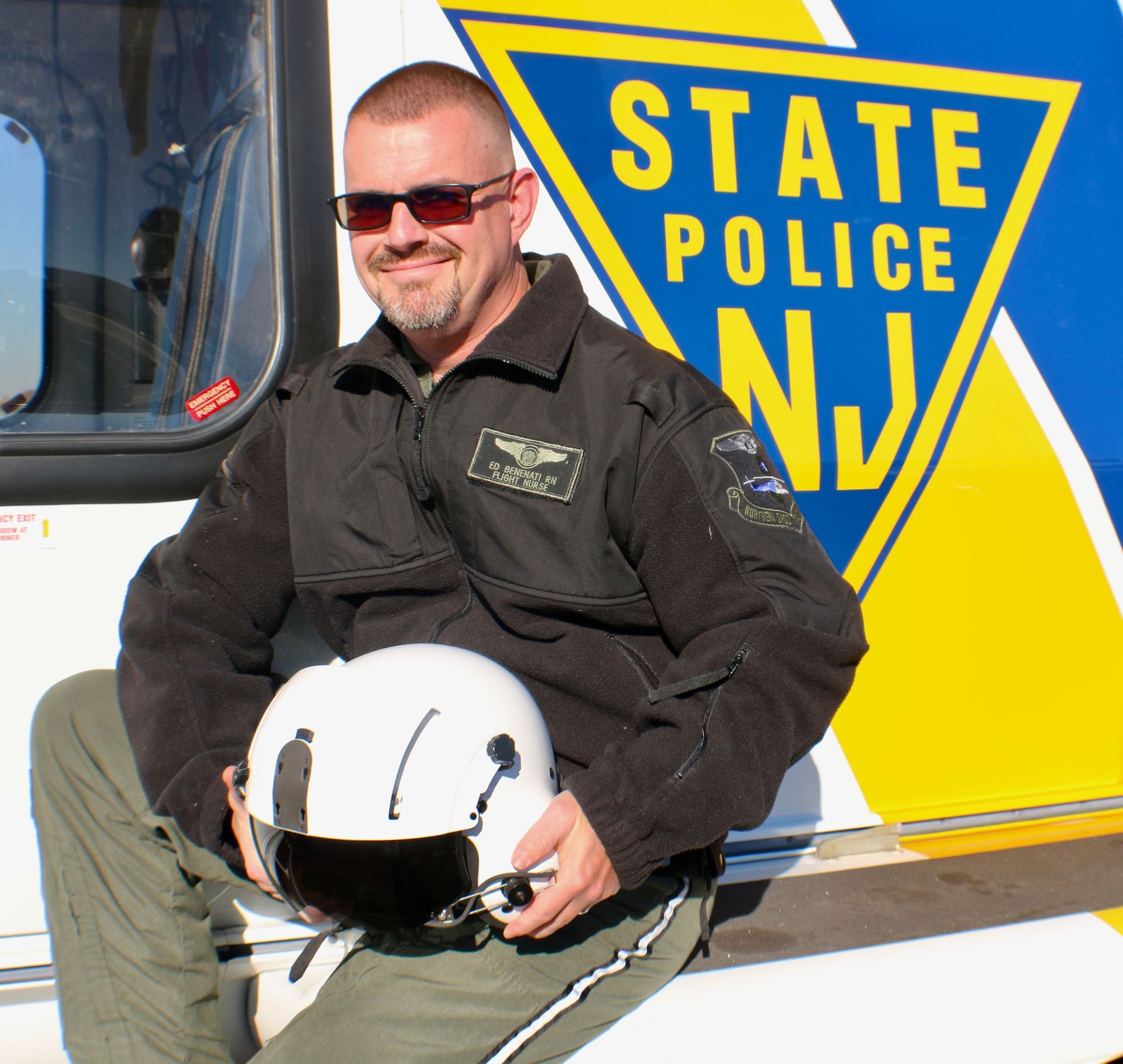 A woman is sitting on the side of a state police helicopter