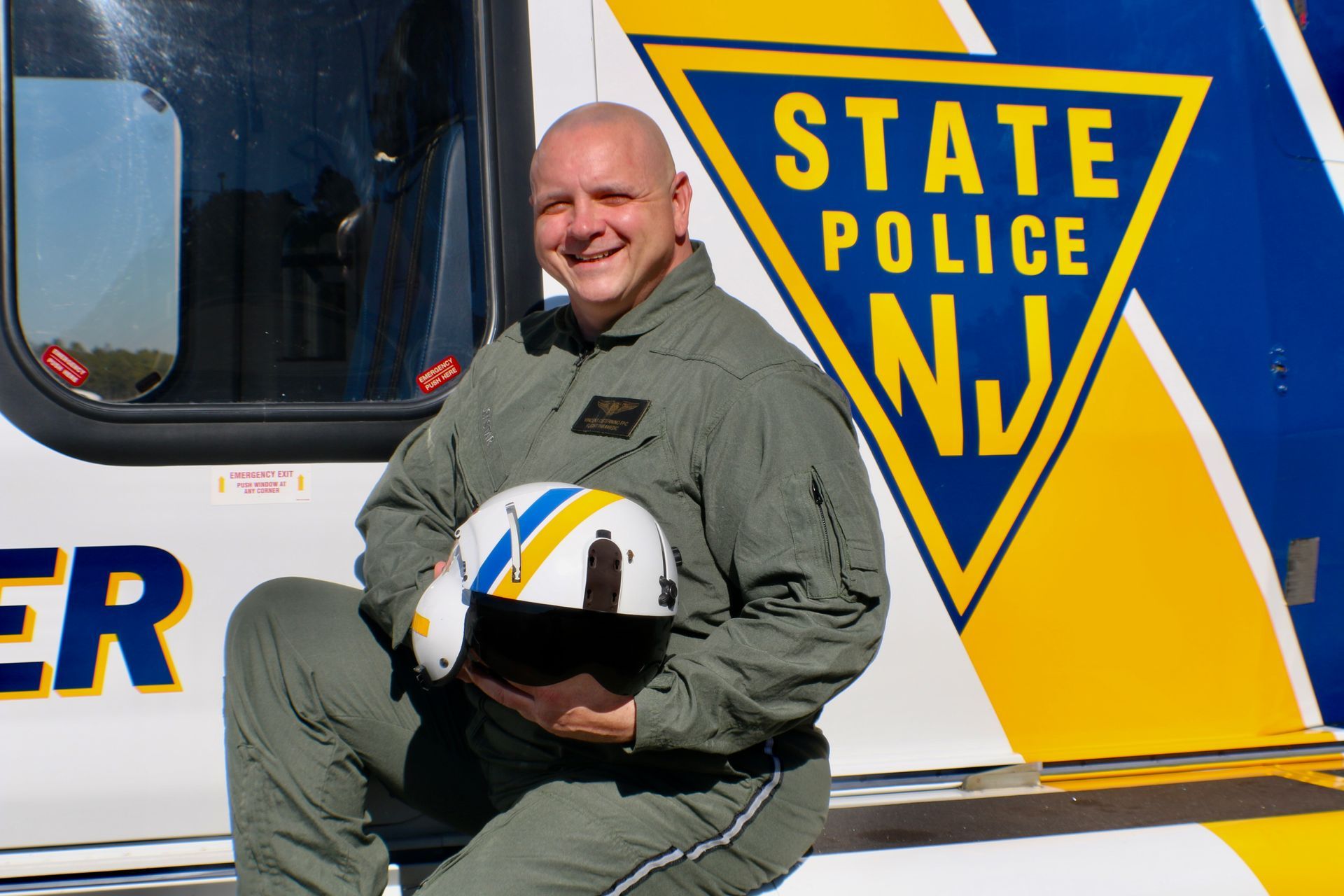 A man in a state police uniform holds a helmet