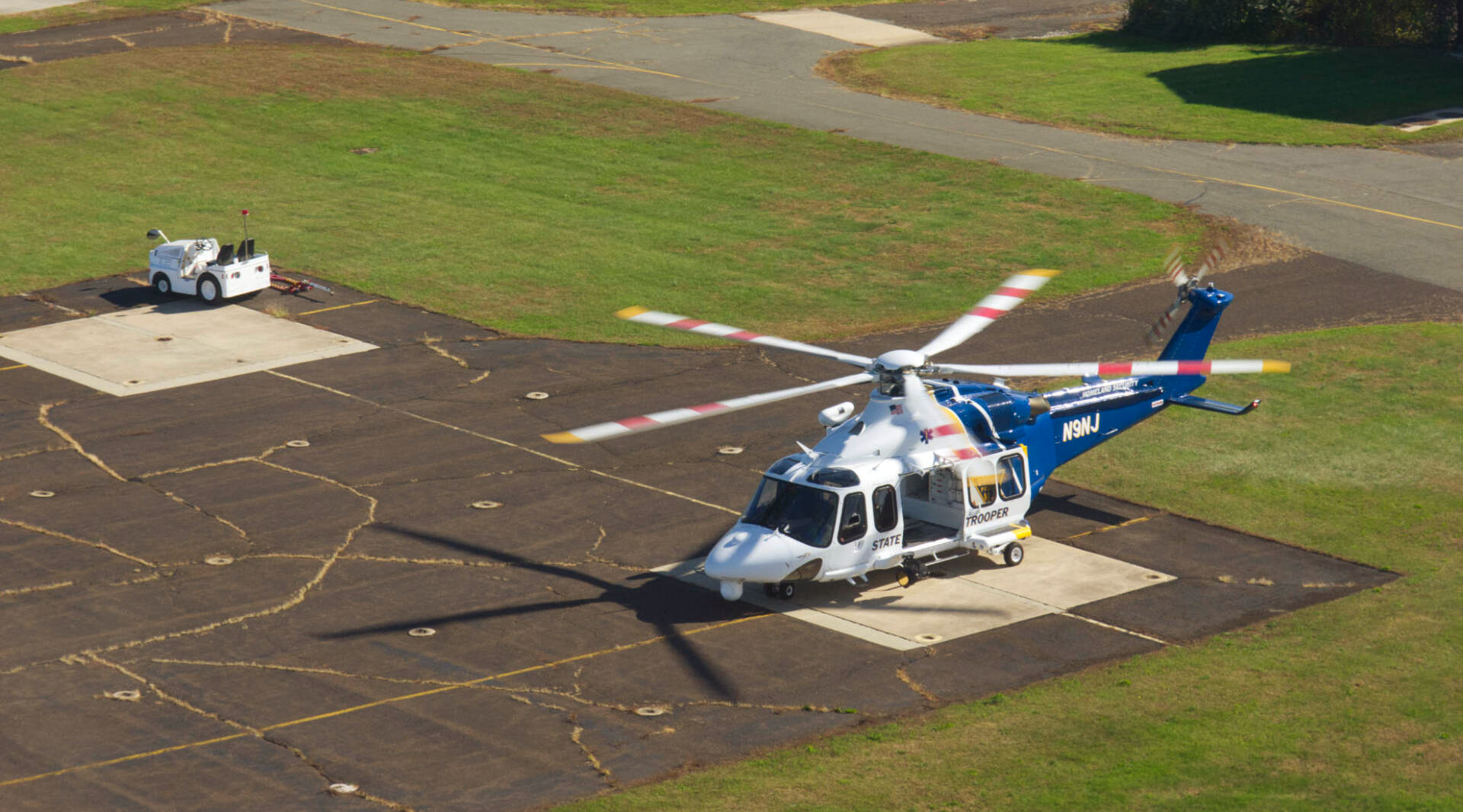A blue and white helicopter is parked on a runway