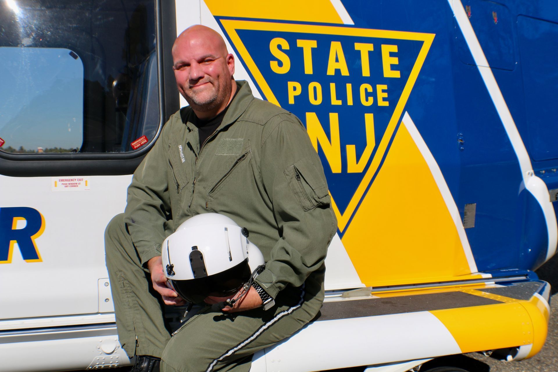 A man sits on the side of a state police helicopter
