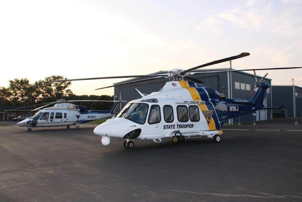 Two helicopters are parked next to each other on a runway