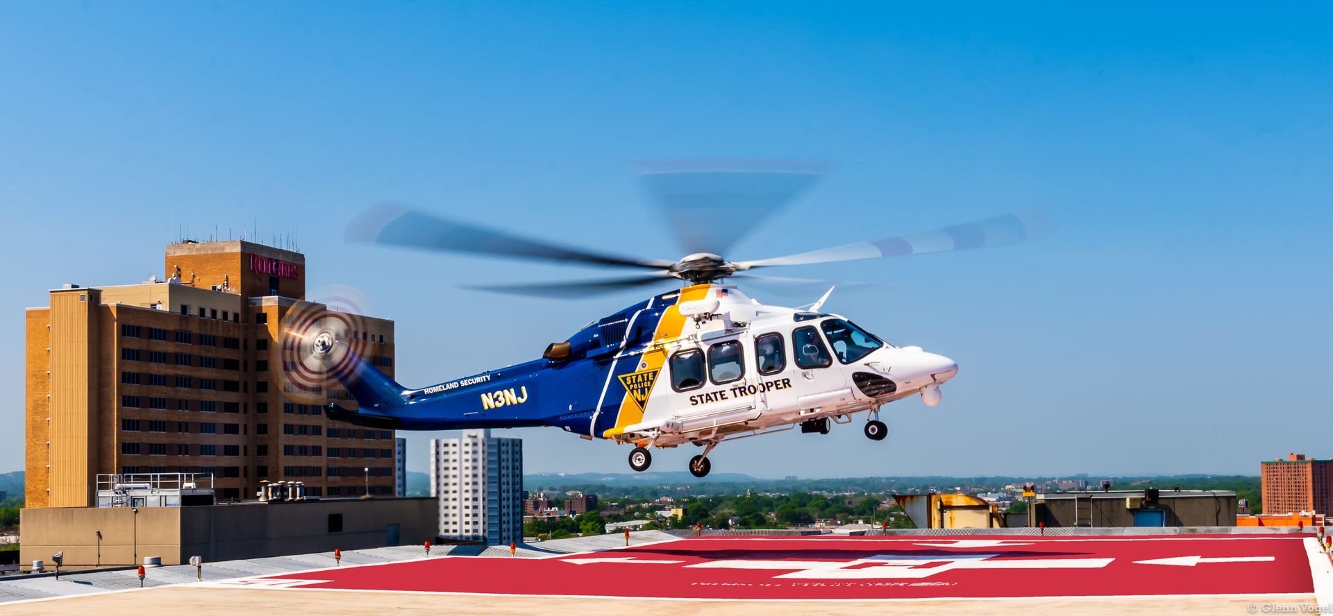 A blue and white helicopter is taking off from a runway