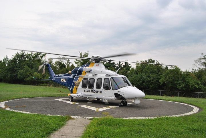 A blue and white helicopter is parked on a runway