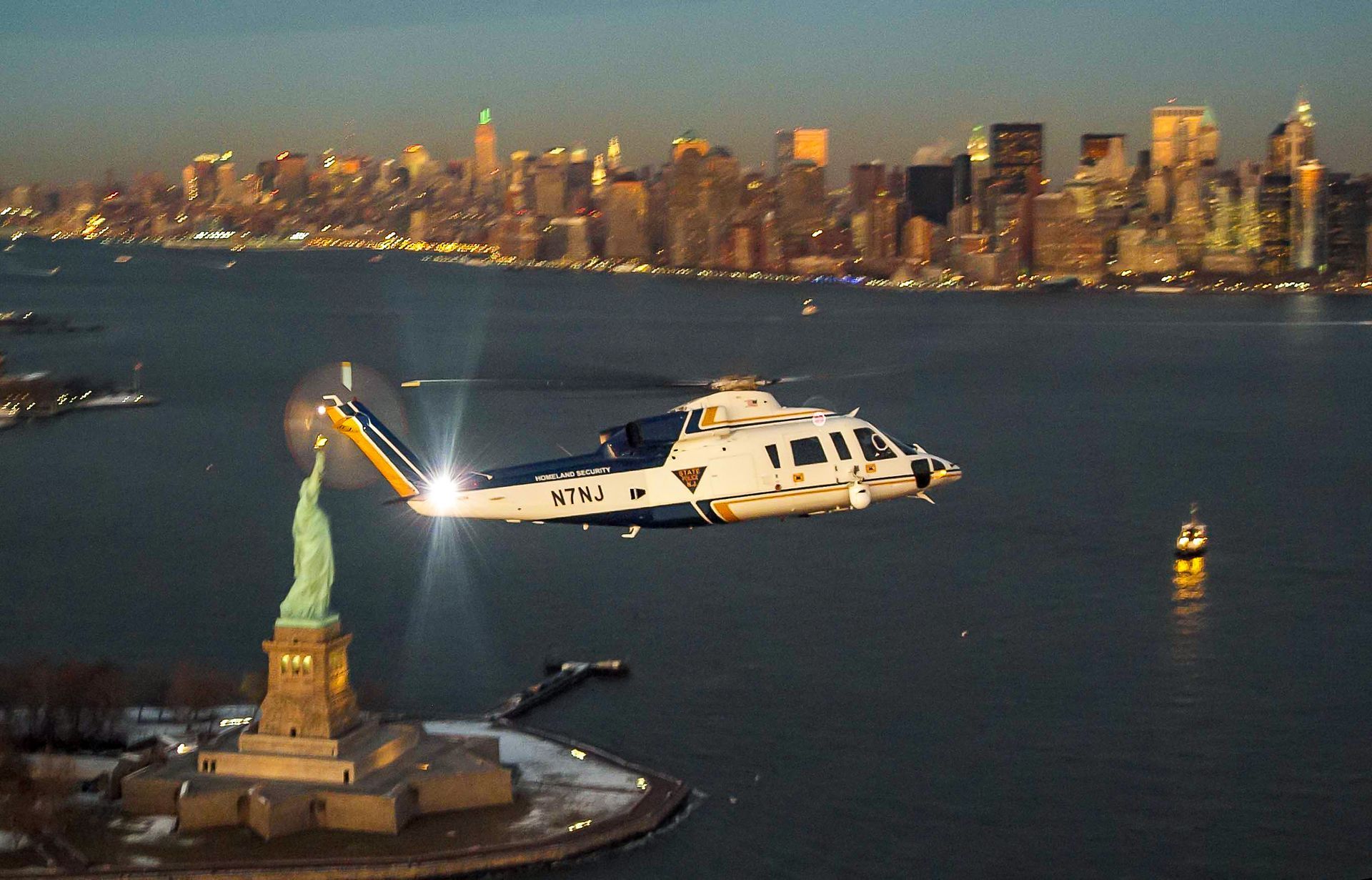 A helicopter is flying over the statue of liberty