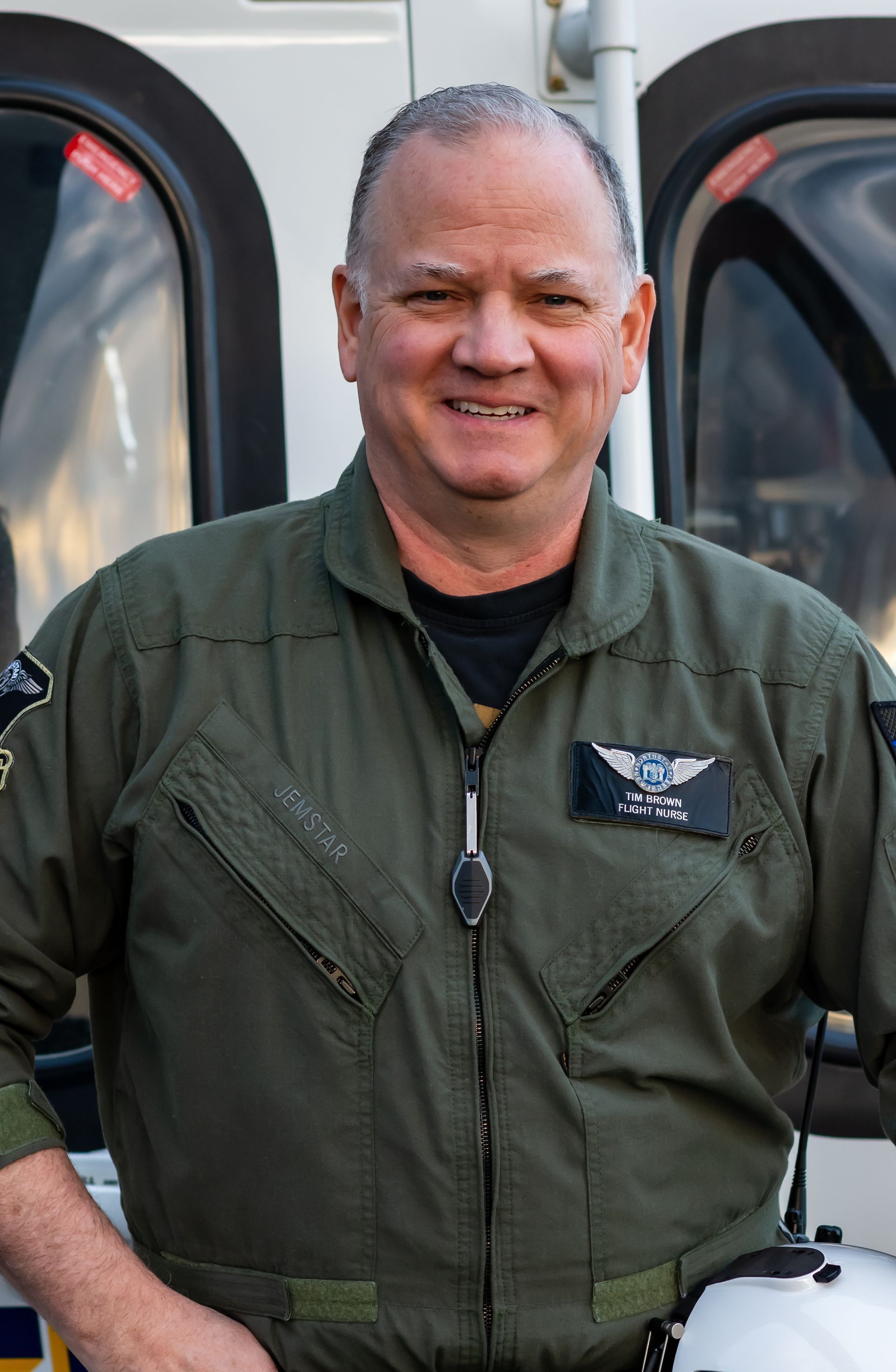 A man in a military uniform is standing in front of a helicopter
