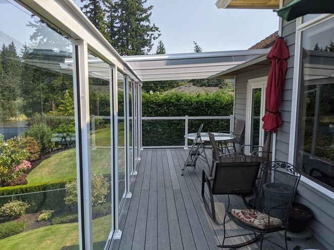 Wooden gazebo with translucent roof, in a wooded area. Interior table and chairs visible.
