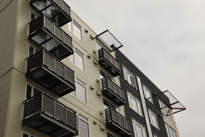 Backyard patio with a black railing, clear roofing, and landscaping.