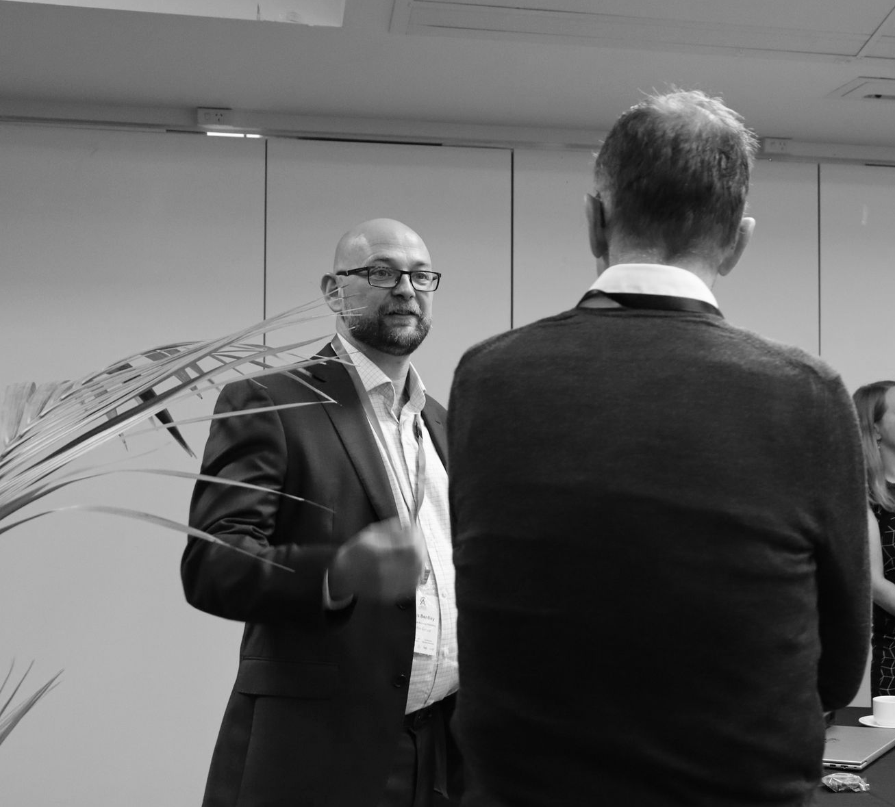 People networking at a conference table in a meeting room, with one man speaking and others listening.